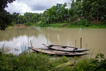 Bangladesh is a riverine country. A quiet beautiful small river. There are two boats tied up at the wharf.
