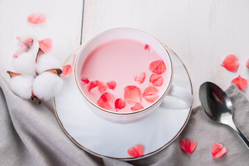 Trendy vegan tea on white background. Pink matcha with rose petals in a cup. Relaxing drink recipe for sleepy times.