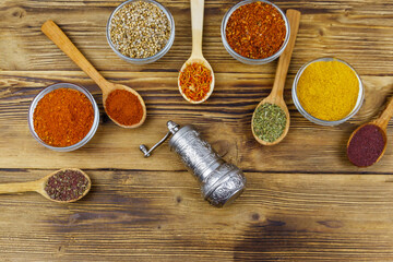 Set of different aromatic spices and spice mill on wooden table. Top view