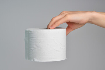 Hand with tissue paper on white background. Hand holding a roll of toilet paper. Close up of a woman hand using detail of one single clean toilet paper roll on white background. 