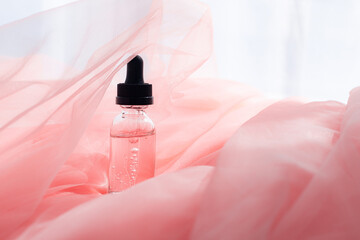 Hyaluronic acid bottle on coral fabric . Beauty container. Skin care. Vitamins for the skin....