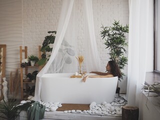 young beautiful woman takes a bath, makes a dry brush massage, esthetics and body parts, a woman smears herself with cream after a shower