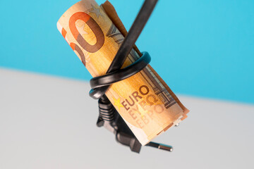 Euro bank note tied in a knot with an electric cable with a plug on a blue white background - obrazy, fototapety, plakaty