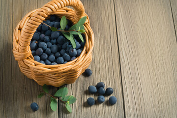 Wild forest blueberries in a small basket on a wooden table