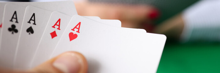 Man holding winning poker hand at table closeup