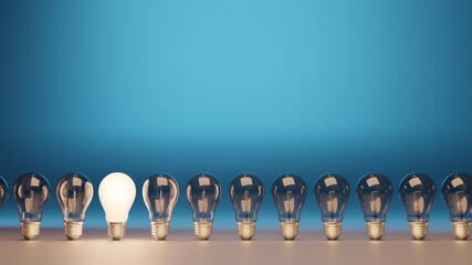 light bulbs in a row on blue background with one illuminated and space for text	
