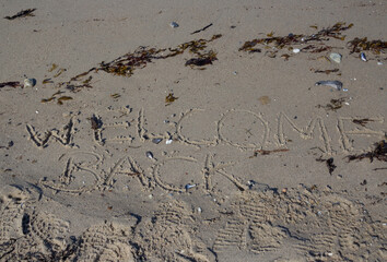 the words welcome back written in the sand at the sea, concept for tourists for reopening travelling after corona virus pandemic