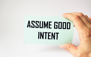 Assume good intent, card is held by female hand on white background. Good intentions on sticker, positive and personal development concept