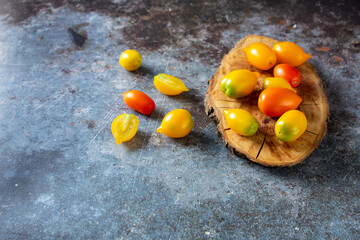 various colorful ripe tomato on rustic blue background. Cooking from yellow orange and red cherry tomatoes.