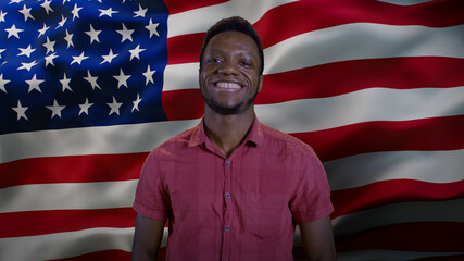 Black man smiling for camera against American flag
