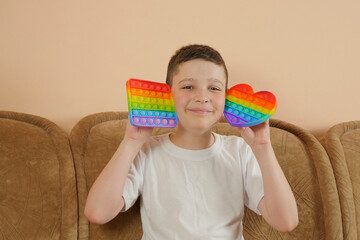 Little boy playing with a modern drink toy. Colorful and vivid toy pop it, anti-stress. Pop it trend.  Popit. Copy space