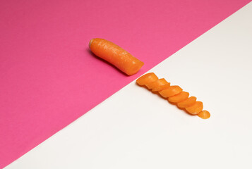 Carrot cut in slices on warm pink white background. Minimal food concept.