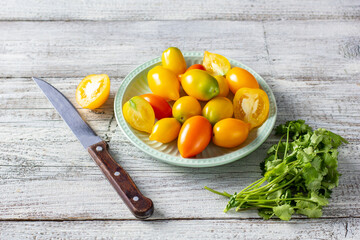 various colorful ripe tomato on white wooden background. Cooking from yellow orange and red cherry tomatoes.