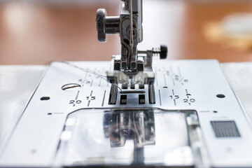 Needle presser foot with thread of industrial sewing machine for sew cloth close-up.