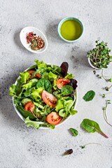 Fresh salad with fresh vegetables, ripe tomatoes, cucumber, lettuce and microgreen  in a bowl on a...