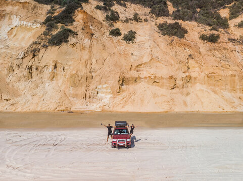Queensland, Australia - 25 August 2020: Aerial view of a couple standing with an off road vehicle on Rainbow beach, Queensland, Australia. - Powered by Adobe