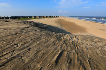 Wooden houses and sand dunes against a blue sky background