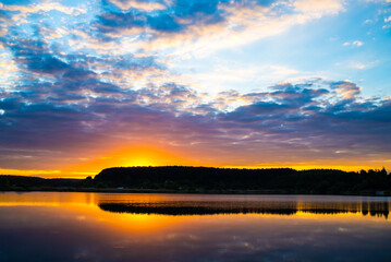 Fototapeta na wymiar sunset at coast of the lake. Nature landscape. reflection, blue sky and yellow sunlight. landscape during sunset.