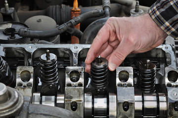 Car mechanic fixing modern diesel engine, closeup of hand holding injector