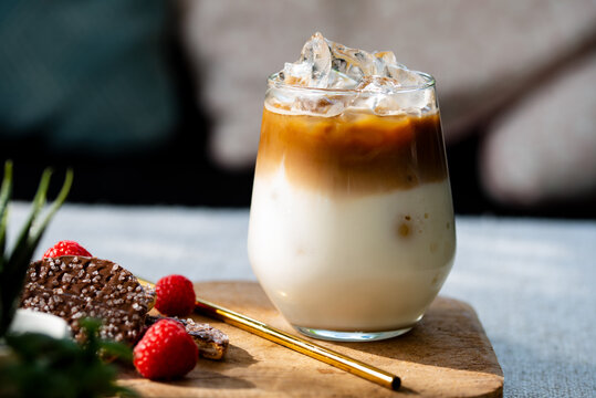 Refreshing drink for summer. A glass of iced coffee latte with chocolate cookies on coffee table near the window in the living room.
