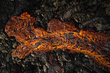 Aerial view of lava streaming down the mountain ridge, view of a river of lava flowing from the craters in Grindavík, Southern Peninsula, Iceland.