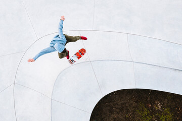 Aerial view of professional skateboarder jumping and doing kick flip trick in urban skate park in Kaunas, Lithuania.