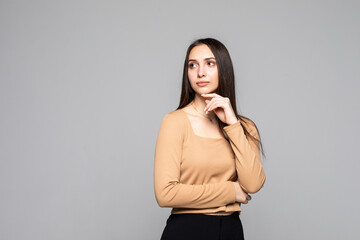 Close up portrait of charming and lovely young woman looks away keep her hand on the chin isolated on gray background