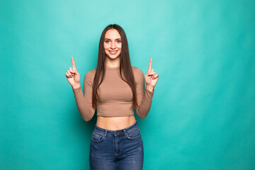 Portrait of woman pointing fingers promoting looking up blank space isolated on turquoise background