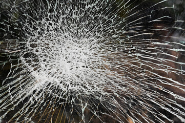 Broken car windshield with cracks. Smashed glass on a black background, close up.  Cracked glass in accident.
