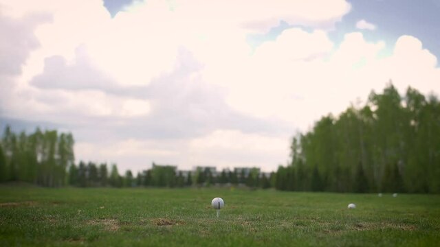 Hitting a golf ball with a club.  