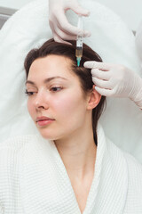 Naklejka premium A woman getting a shot in the head at a cosmetology clinic. mesotherapy for hair growth.