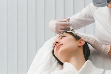 A woman getting a shot in the head at a cosmetology clinic. mesotherapy for hair growth.