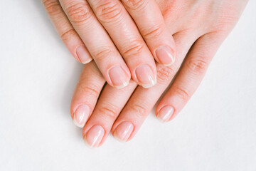 Woman in a nail salon receiving a manicure by a beautician with nail file. Beauty and hand care close-up.