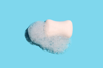 Soap bar in foam on blue background.