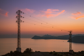 Fototapeta premium High voltage towers on coast at sunset