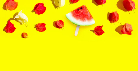 Watermelon slice popsicle with bougainvillea flowers on yellow background.