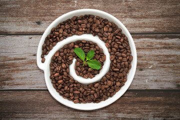 Top view on a spiral with espresso beans on a brown background.