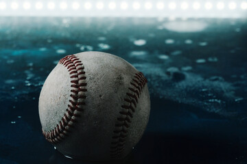 Dark moody baseball in water with night lighting in background for sport.