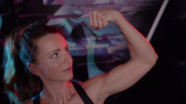 Biceps. Athletic woman shows biceps on her arm.