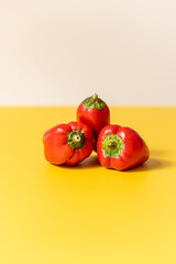 Front image of three red peppers on yellow table