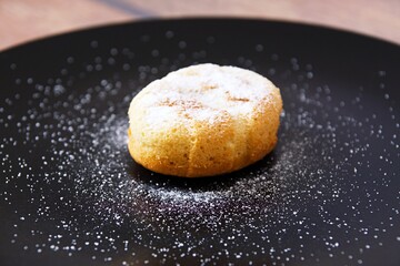 Sweet juicy muffins sprinkled with vanilla sugar on a black plate