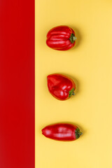 three small red peppers on a yellow background