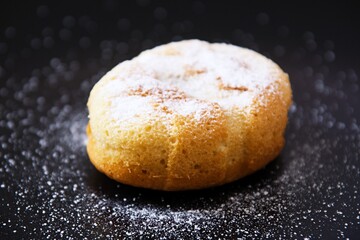 Sweet juicy muffins sprinkled with vanilla sugar on a black plate