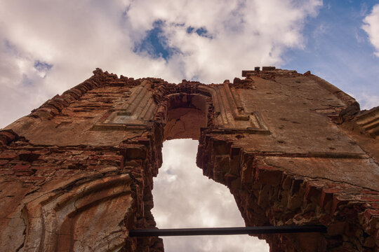 The destroyed wall of an old abandoned church made of brick with showered plaster in cloudy weather. Russia, Smolensk region, 1753.