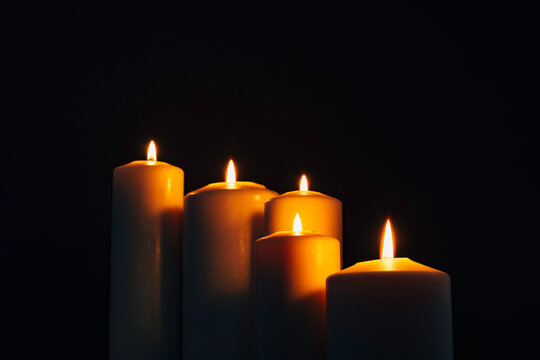 Five burning candles on black background