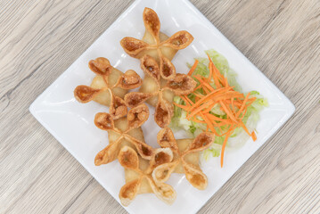 Overhead view of deep fried ranggoon wontons filled with delicious stuffings and presented in a star shape on a plate