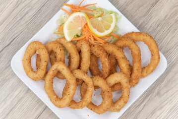 Overhead view of deep fried calamari rings arranged on a plate as an appetizer for your meal