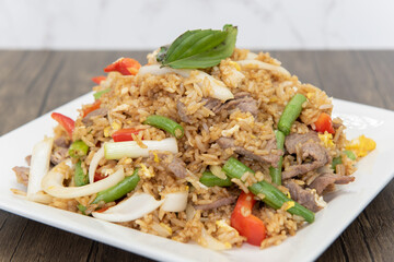 Huge pile of spicy fried rice topped with meat and vegetables on a plate to fulfill that spicy...