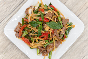 Overhead view of delicious pile of stir fried vegetables, bamboo shoots and meat topped with a star shaped basil leaf