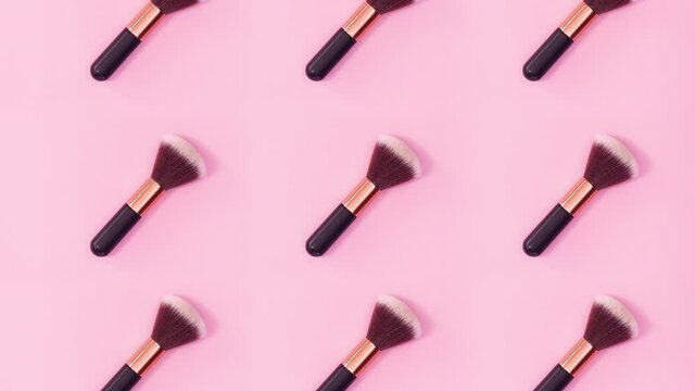 Beauty concept pattern made of make up brushes rotate on bright pink background. Stop motion